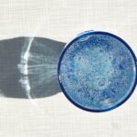 Uomo che controlla il livello di idratazione con un bicchiere d'acqua e un termometro in mano.