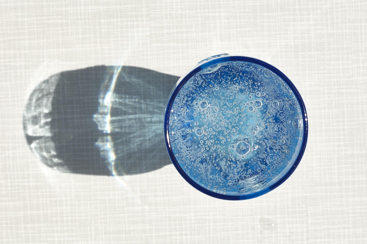 Uomo che controlla il livello di idratazione con un bicchiere d'acqua e un termometro in mano.