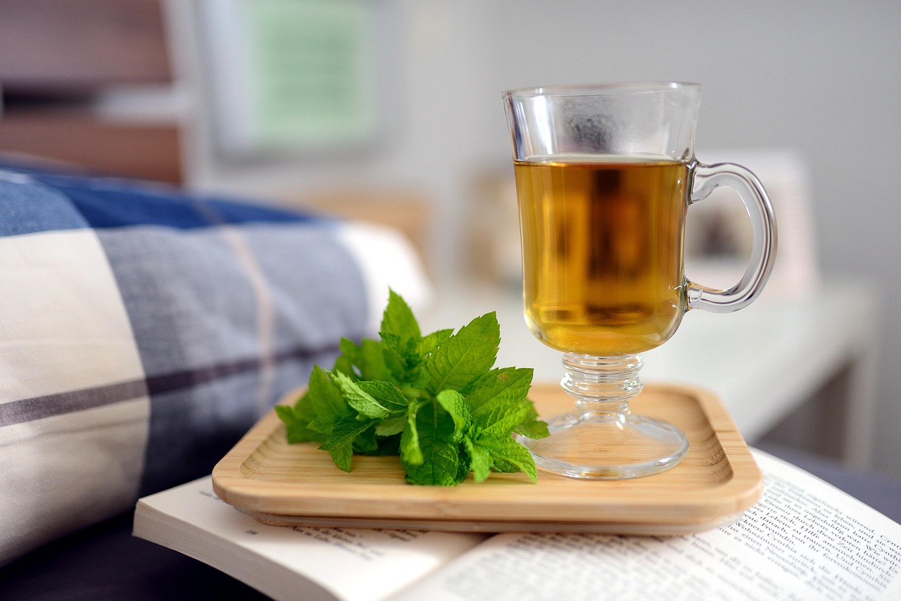 Tazza di tisana fumante con erbe naturali su un tavolo, simbolo di rimedi per migliorare il sonno.